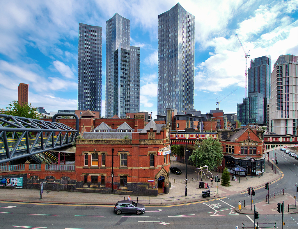 Four Deansgate Square towers rising behind red-brick warehouses at Knott Mill