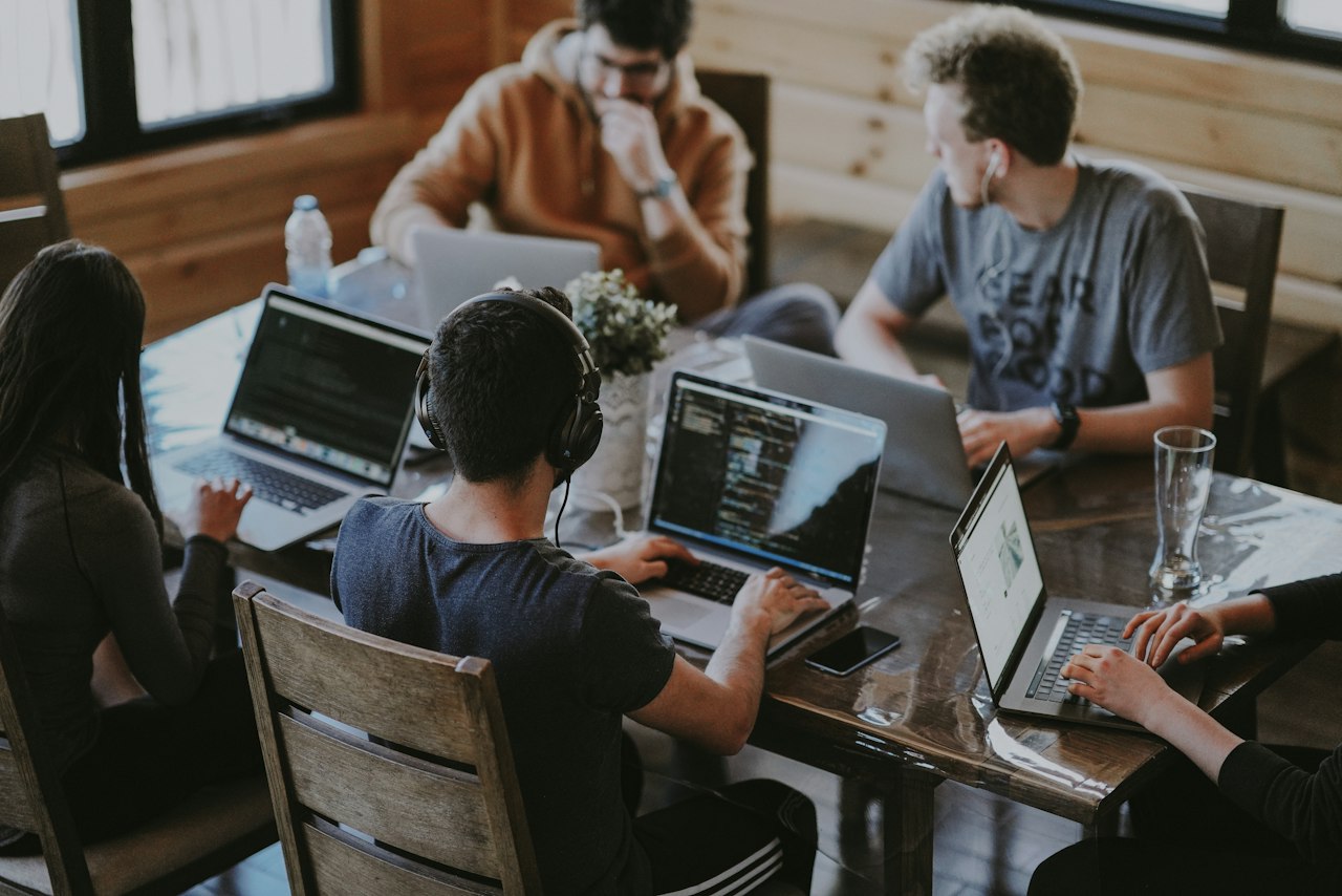Engineers collaborating around laptops in a bright office